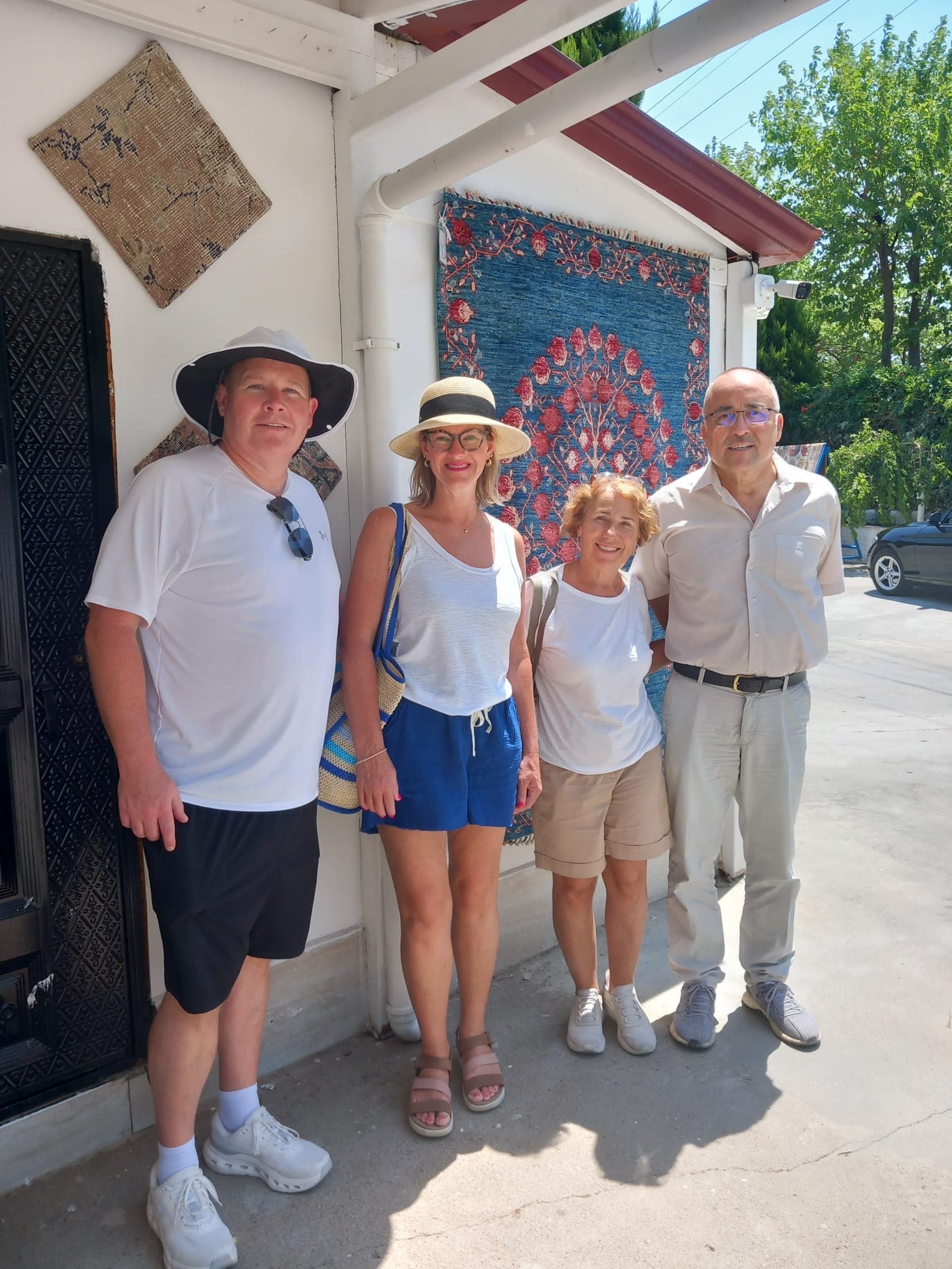 Gäste einer privaten Tour posieren mit ihrem Guide neben traditionellen türkischen Teppichen.