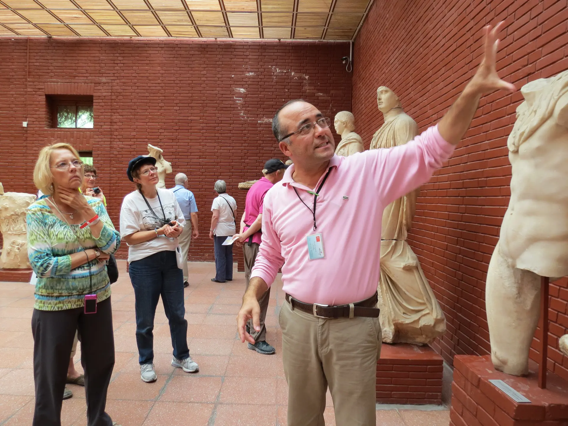 Expert tour guide explaining ancient Roman marble statues inside the Terrace Houses museum in Ephesus.