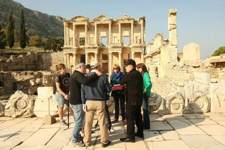 A private tour guide providing historical insights to a small group in front of the iconic Library of Celsus facade.