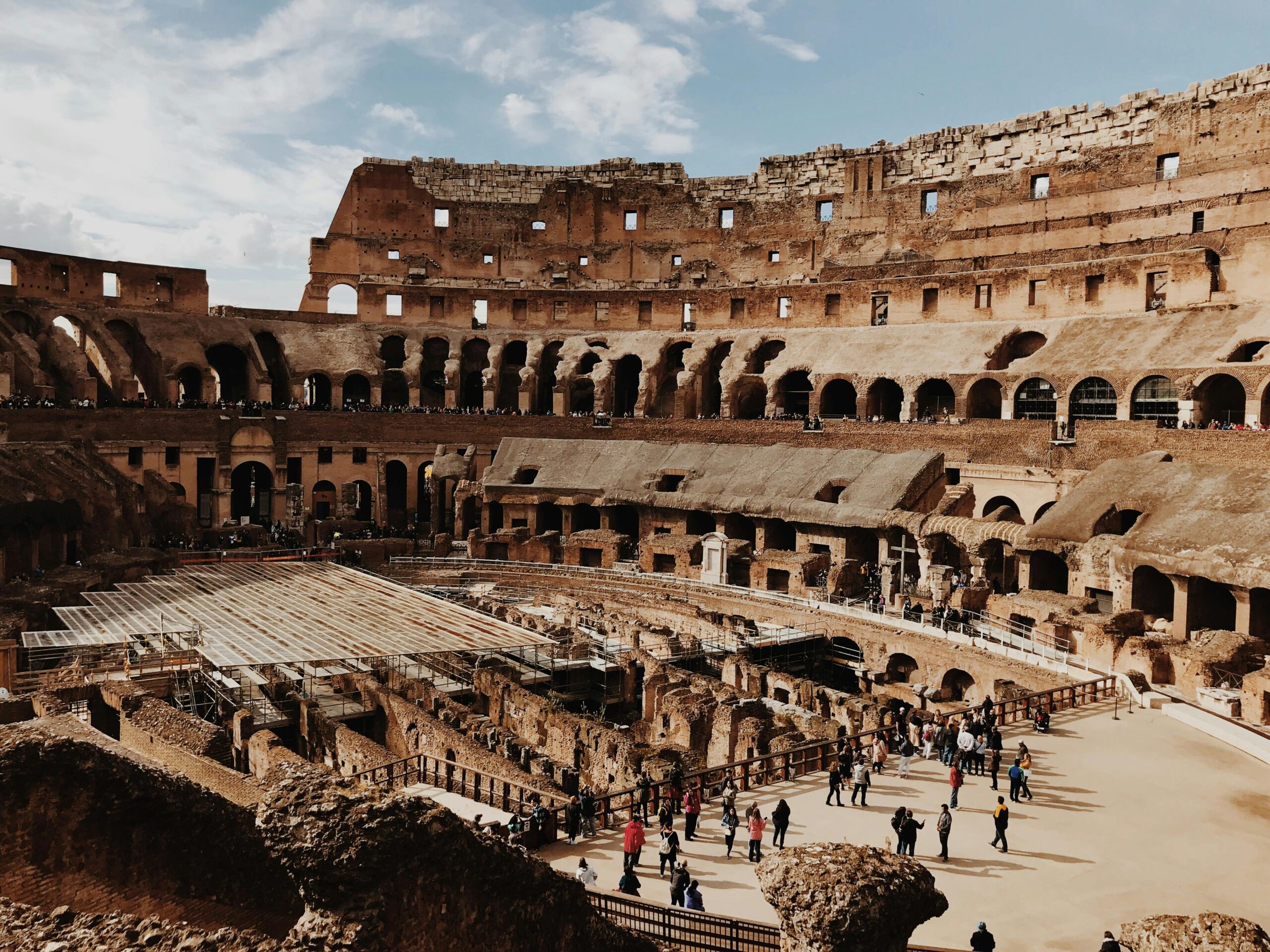 View of the iconic Colosseum in Rome with tourists exploring the ancient amphitheater.