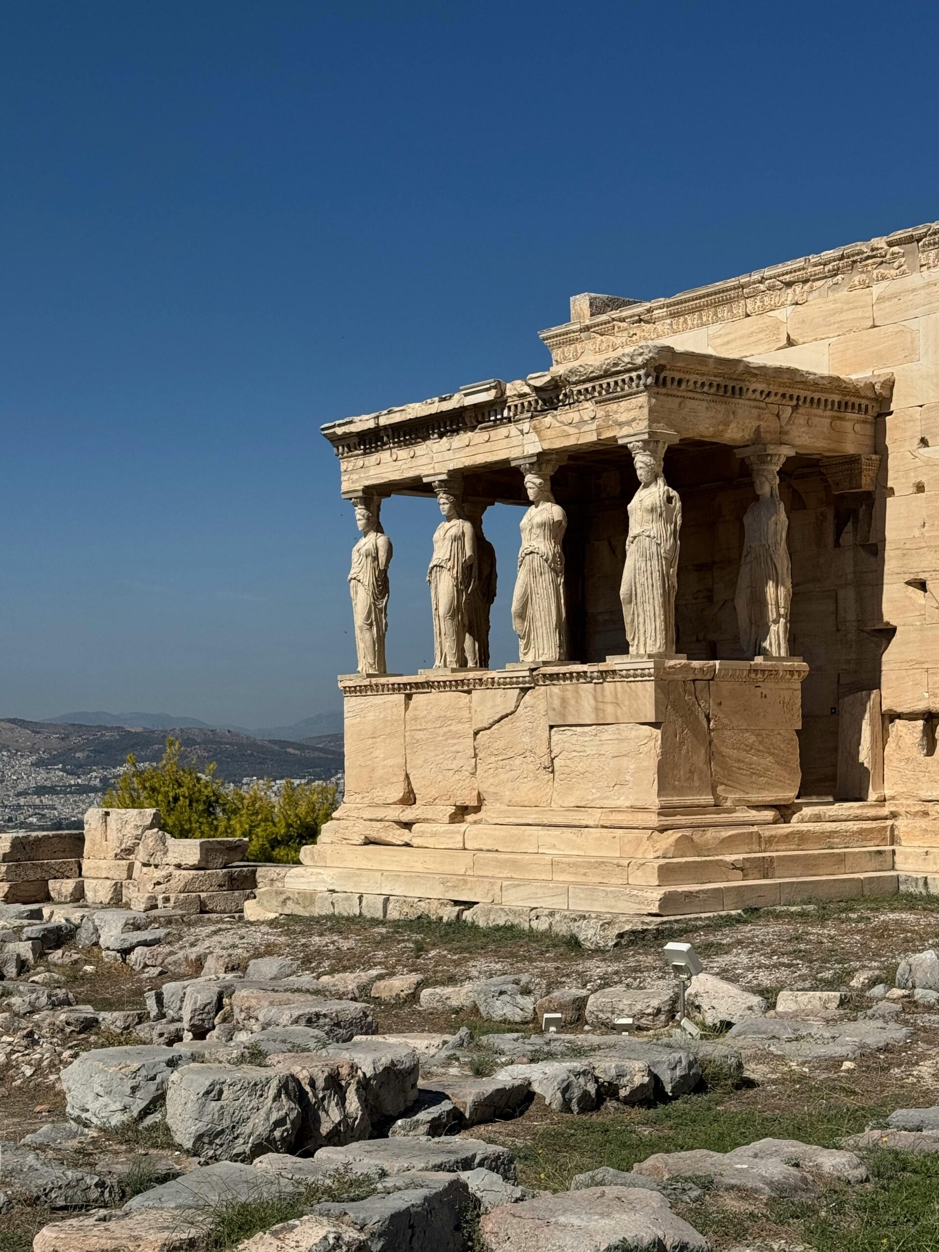 View of Erechtheion Caryatids on the Acropolis of Athens under clear blue sky.