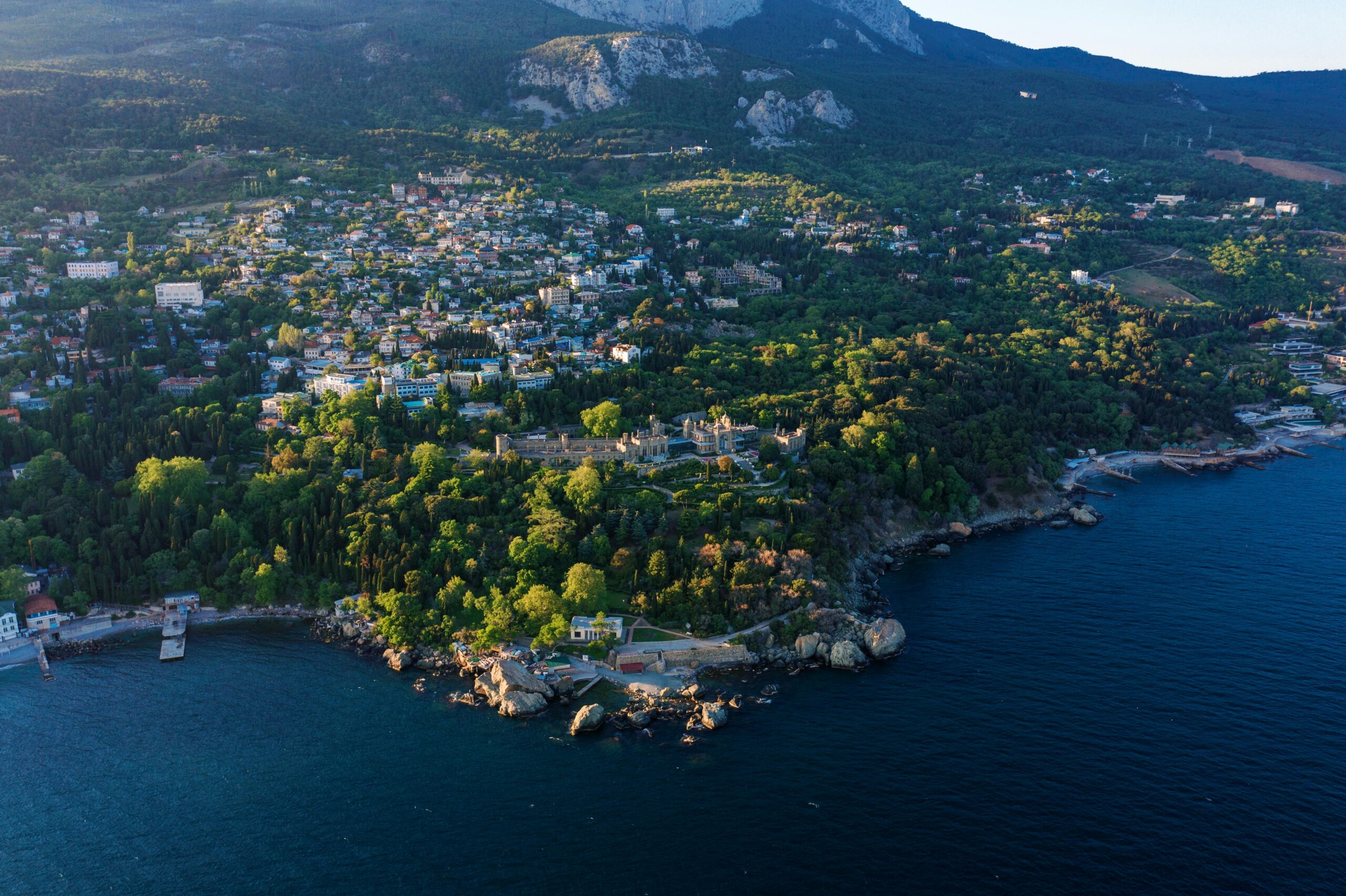 Scenic aerial view of Alupka, Crimea featuring the picturesque coastline and lush greenery against clear blue water.