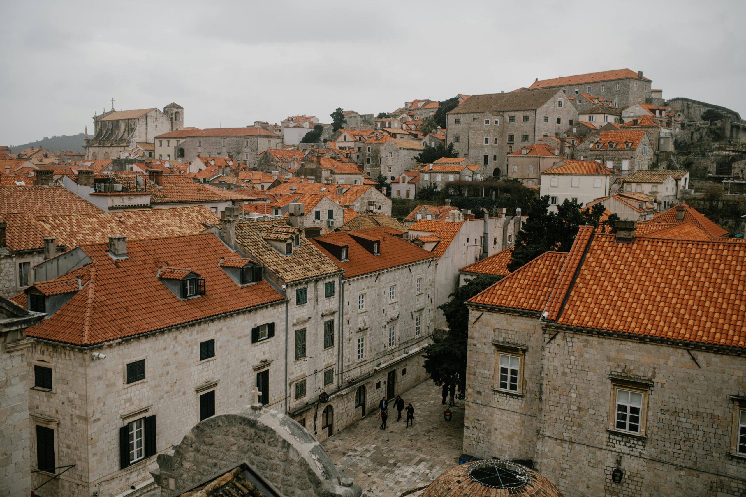 From above of aged shabby houses with bright orange roofs under gloomy cloudy sky